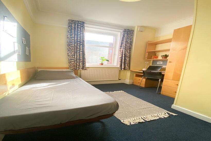 A bright and tidy single bedroom with a comfort...